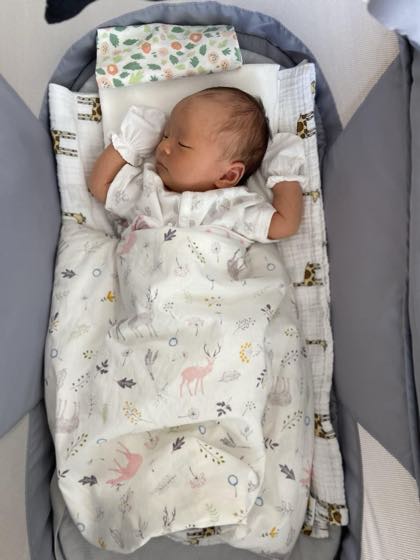 ベビーベッドで背中をつけて平らに眠る新生児