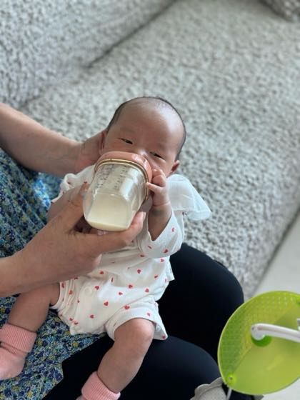 親の腕に抱かれて哺乳びんで少しずつ水分をとる赤ちゃん