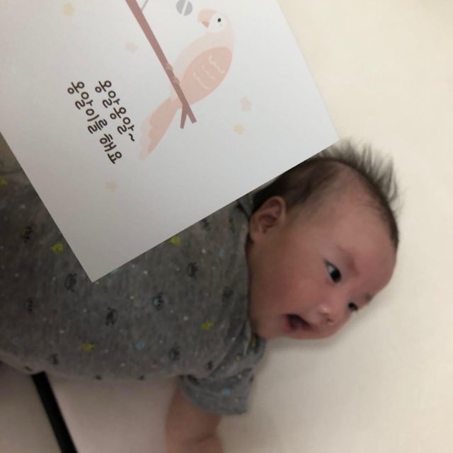 배를 바닥에 대고 엎드려 고개를 들고 그림카드를 바라보는 아기