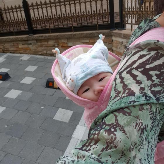 모자를 쓰고 포대기에 안겨 가을 나들이를 나온 아기