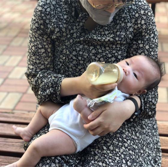 親の腕に抱かれ、哺乳びんで少しずつ水分をとる赤ちゃん