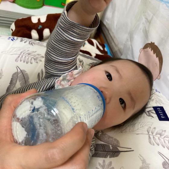 어른이 젖병을 물려 아기에게 수분을 먹이는 모습