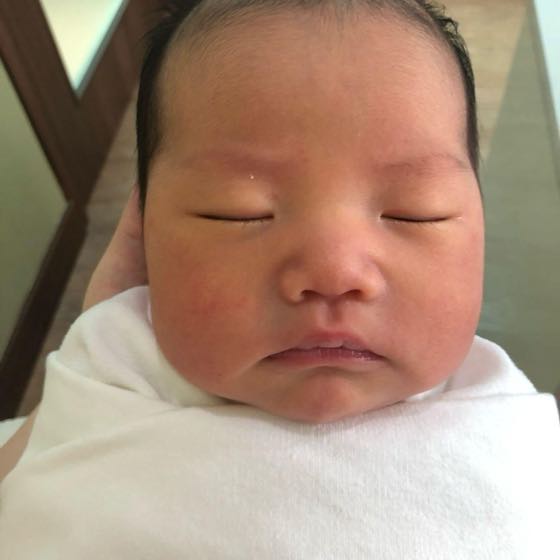 포근한 속싸개에 싸여 어른 손에 안겨 잠든 어린 신생아