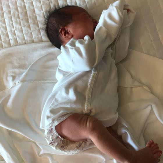 A baby in a diaper resting comfortably on a bed