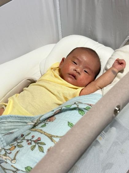 A newborn resting comfortably in a bassinet in a bright room