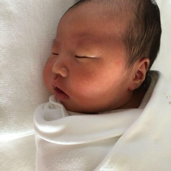 A newborn swaddled in white cloth, sleeping
