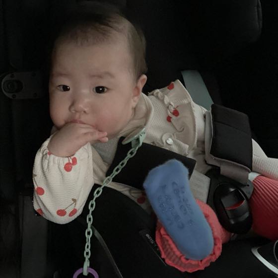A baby chewing on a hand and drooling because the gums are itchy