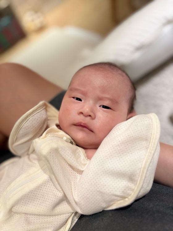 A newborn wrapped in a towel, comfortably cradled