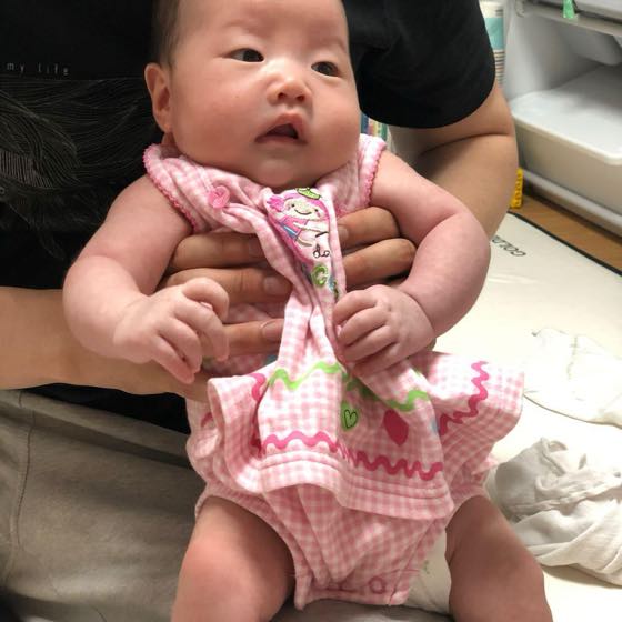 어른의 두 손으로 받쳐 안은 어린 아기의 상태를 살피는 부모