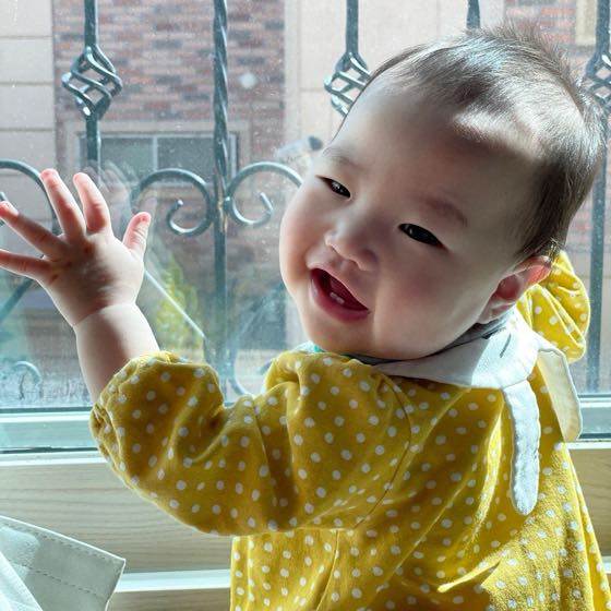 창가에서 손을 흔들며 웃는 아기